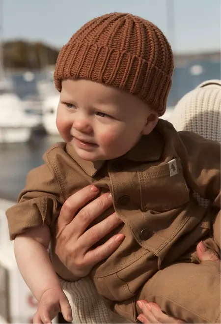 baby boy in a brown beanie and brown jumpsuit