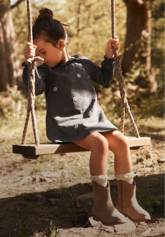 girl in western collection dress swinging on swing