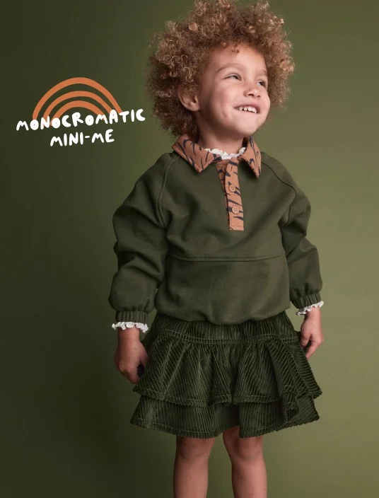 toddler girl in green sweatshirt with tiger print accents
