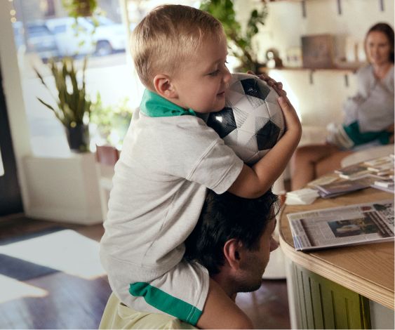 kid on dad's shoulder with soccer ball