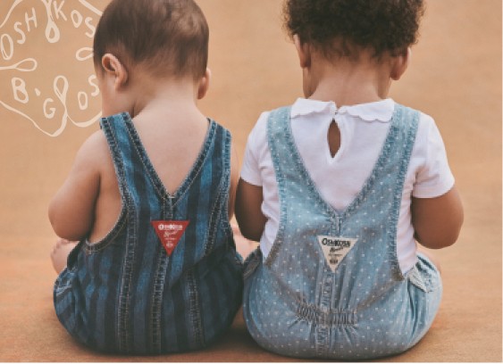 two babies sitting and wearing oshkosh b'gosh overalls