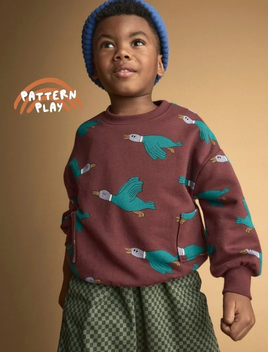 toddler boy in graphic sweatshirt and patterned pants