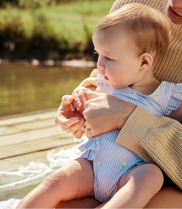 Baby sitting in lap in blue striped one piece