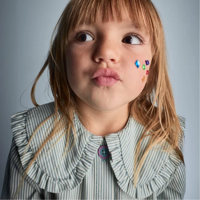 toddler girl making face in collared shirt
