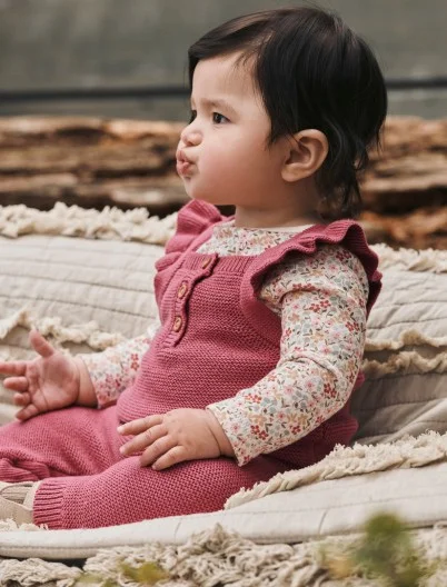 baby girl in knit overalls