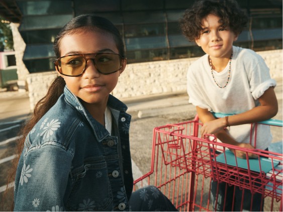 girl in floral denim jacket and sunglasses with boy in white t-shirt