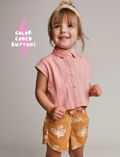 toddler girl in button up top and patterned shorts